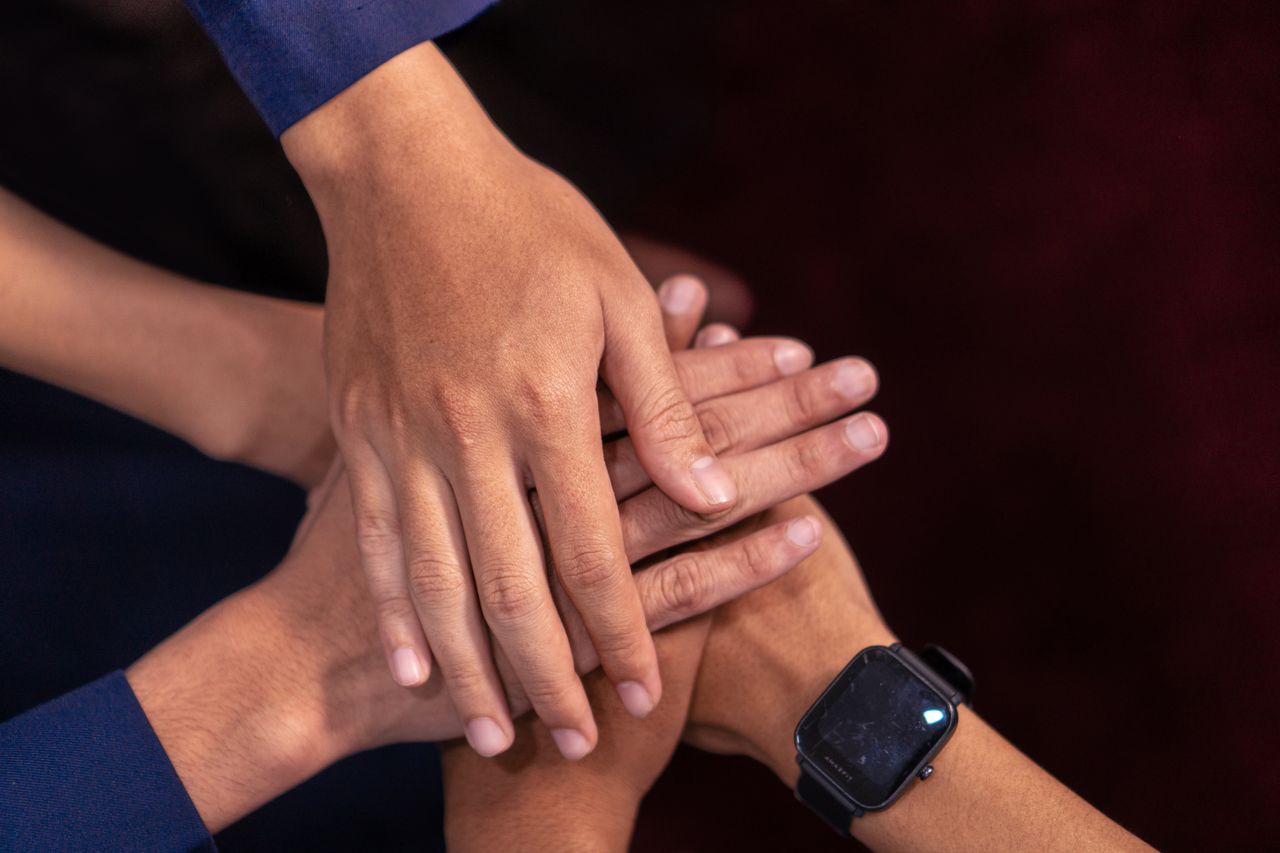 Close-up of diverse hands stacked together, symbolizing unity and teamwork.